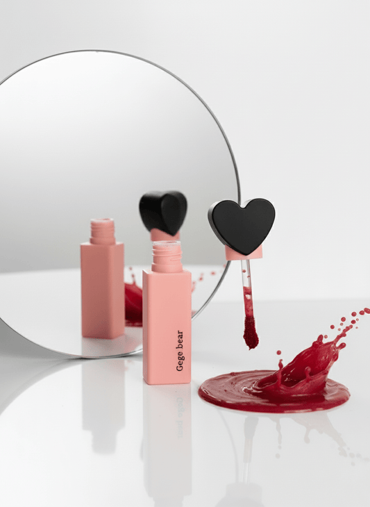 Gege Bear Lip stain lipstick with heart-shaped cap and spilled red liquid near mirror